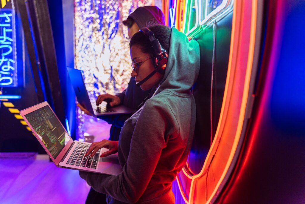 Team of cyber security experts working on laptops in a vibrant neon-lit room.