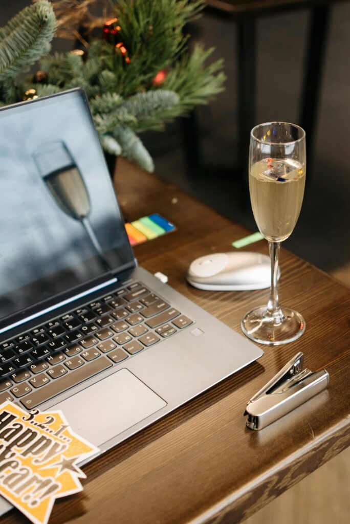A cozy holiday-themed workspace featuring a laptop and a glass of champagne.